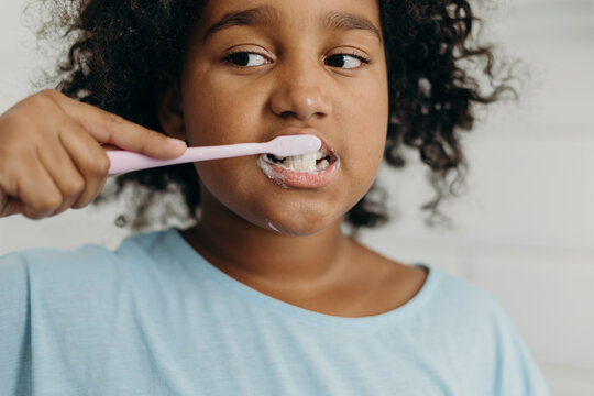 Mixed raced girl brushing teeth