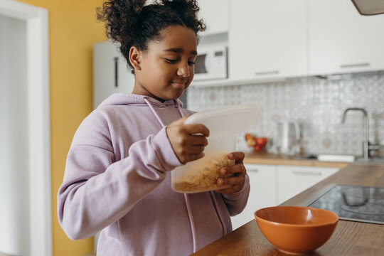 Mixed race girl preparing cornflakes for breakfast