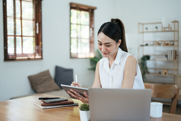 Yound lady working from home using digital tablet in her lovely house.