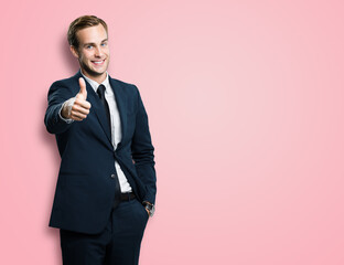 Excited businessman showing thumb up like sign gesture, in black confident style suit, over rose...