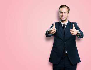 Cheerful smiling businessman in black confident suit showing two thumbs up like hand gesture, over...