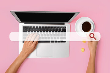 Woman with cup of coffee using laptop on pink background, top view. Concept of search