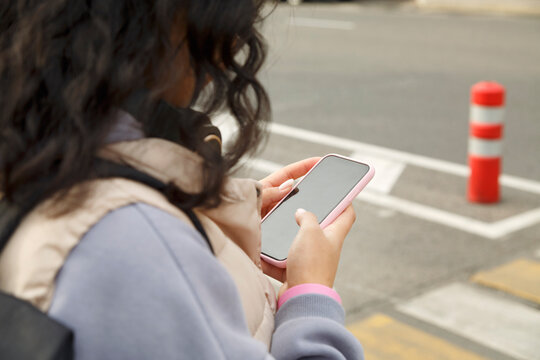 Anonymous brunette using smartphone near crosswalk