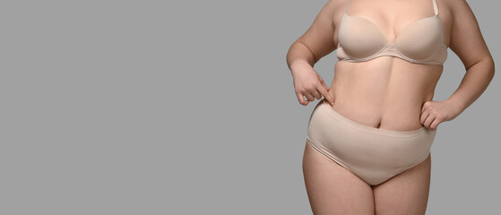Overweight woman on grey background with space for text. Weight loss concept