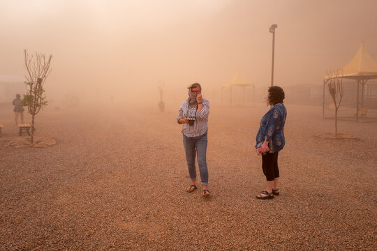 Two women standing in the middle of a sandstorm in the desert.