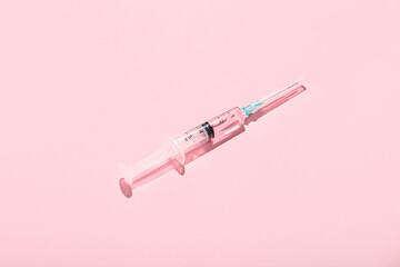 Medical syringe with remedy on pink background