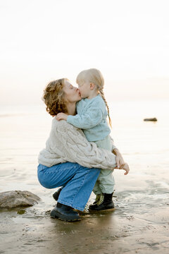 mother kissing daughter on beach