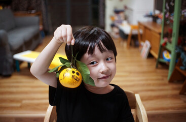 Cute little asian boy making small halloween decorations at home