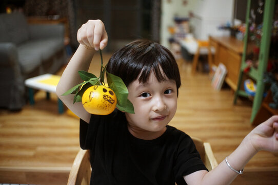 Cute little asian boy making small halloween decorations at home