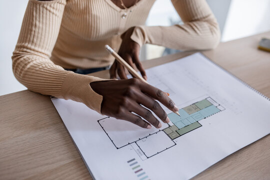 Crop black architect examining draft