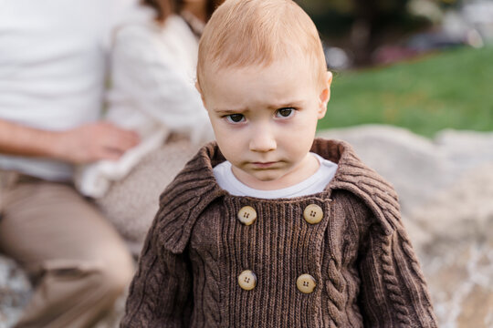 A brown-eyed caucasian baby boy kid toddler in a brown knitted s