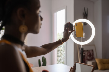 Black blogger advertising compact powder in light room