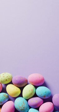 Vertical video of colorful easter eggs on purple background with copy space