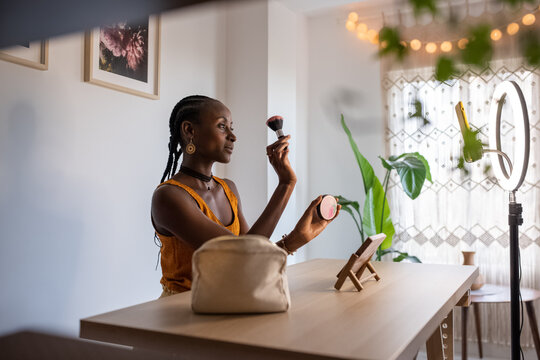 Black vlogger with brush demonstrating blusher