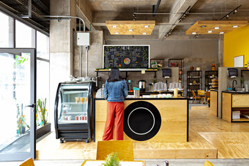 Unrecognizable woman waiting for order at counter of coffee shop