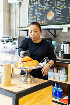 Female cafeteria worker arranging pieces of bread on counter