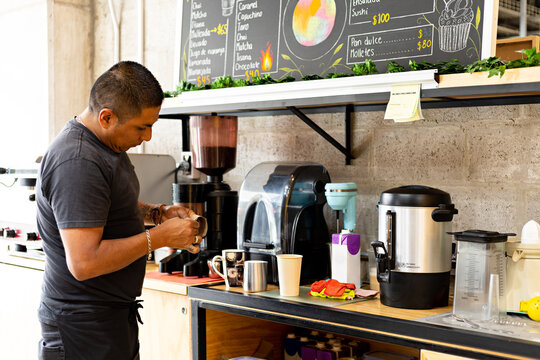 Coffee shop worker preparing cup of coffee for delivery to customer
