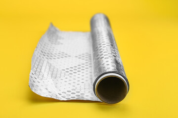 Roll of aluminium foil on yellow background