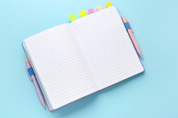 Notebook with sticky notes and pens on color background