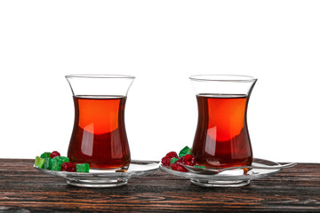 Cups of Turkish tea and sweets on wooden table against white background