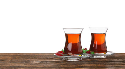 Cups of Turkish tea and sweets on wooden table against white background