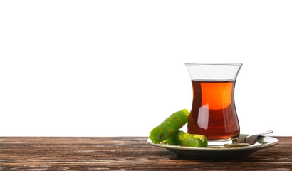 Cup of Turkish tea and sweets on wooden table against white background