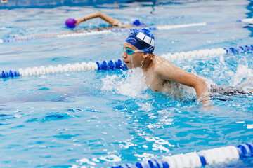 hispanic young teenager man swimmer athlete wearing cap and goggles in a swimming training at the Pool in Mexico Latin America	