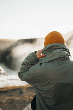 Traveler woman from behind rain jacket enjoying waterfall view