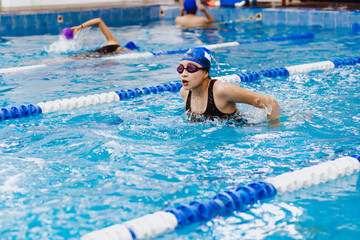 Hispanic teen girl swimmer athlete wearing cap and goggles in a swimming training at the Pool in...