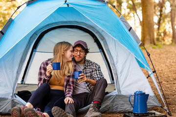 Cute Couple Snuggle Together In Their Tent While Holding Mugs