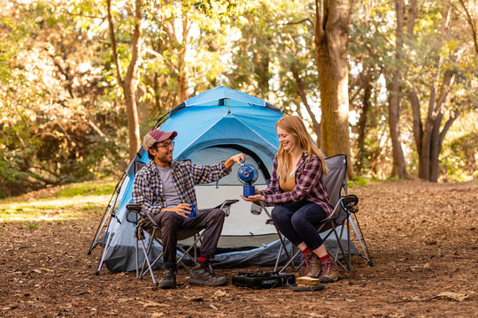 Man Pours Coffee Into Partner's Mug In Front Of Campsite