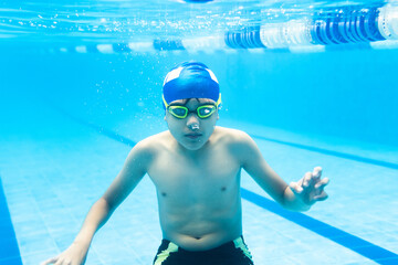 latin child boy swimmer wearing cap and goggles in a swimming underwater training In the Pool in Mexico Latin America	