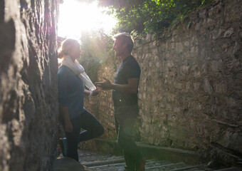 Couple have conversation in corridor between stone walls