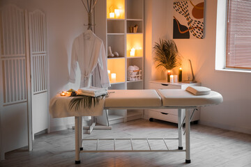 Interior of spa salon with couch, shelving unit and burning candles