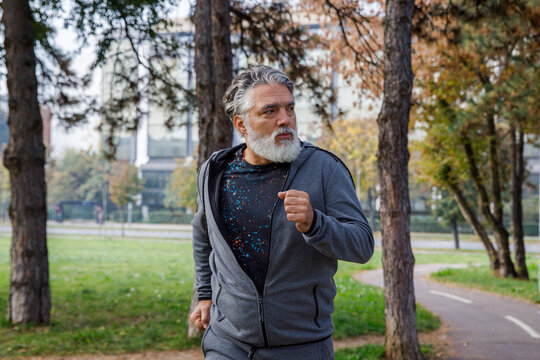 Elderly man looking away while jogging in park 