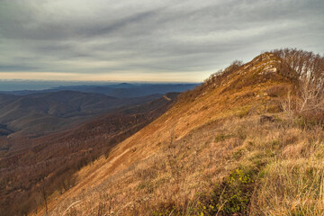 View of the peak of Mount Peus at an altitude of 1000 m. View of the peaks of the Caucasus on a sunny day with blue sky and dramatic clouds. Picturesque view. View of the ridge of mountain peaks.