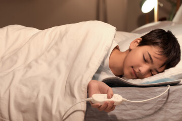 Little boy sleeping on electric heating pad in bedroom at night