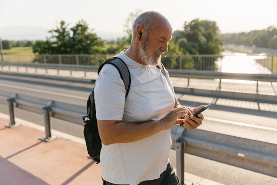 Senior Man Walking Outdoors Using His Smartphone