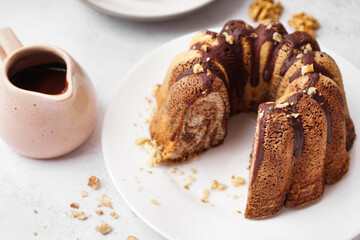 Plate with delicious cake and jug of hot chocolate on light background, closeup