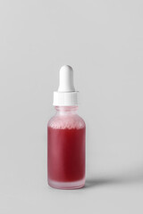 Glass bottle of serum on light background