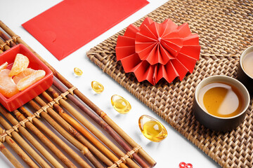 Mats with cups of tea, mandarins and Chinese symbols on white background, closeup