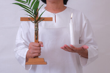 Closeup shot of woman wearing white holding cross and candle on Easter