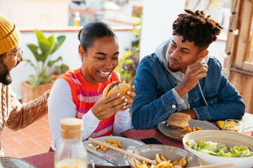 Cheerful diverse friends eating bbq food at rooftop