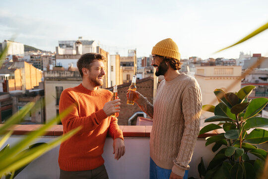 Happy friends drinking beer on rooftop