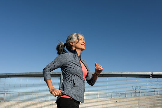 Fit Woman Jogs Along Bridge In City 