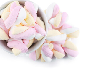 Fototapeta na wymiar Bowl and heap of tasty twisted marshmallows isolated on white background