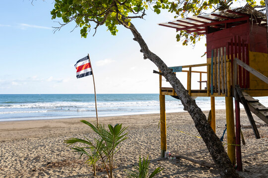 Costa Rica flag on bamboo flagpole on beach colorful lifeguard stand 