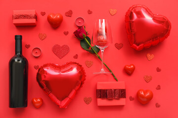 Composition with bottle of wine, gift boxes, balloons and rose flower on red background. Valentine's Day celebration