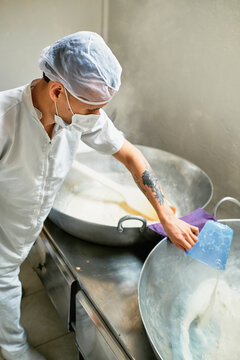 Worker pouring milk into a pot