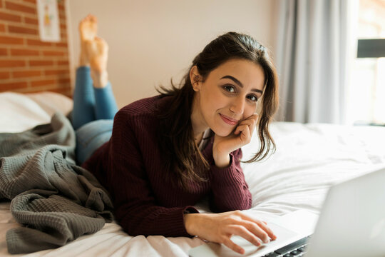 Beautiful woman using laptop from her bed
